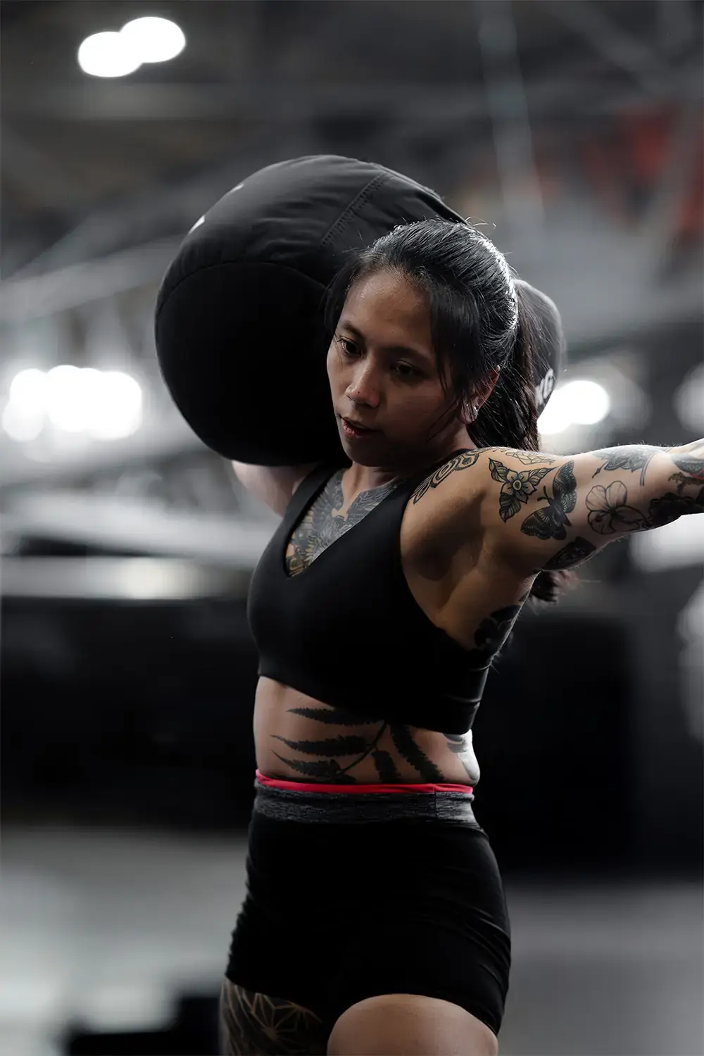 Athlète chargeant un sandbag sur l’épaule dans la zone MetCon X
